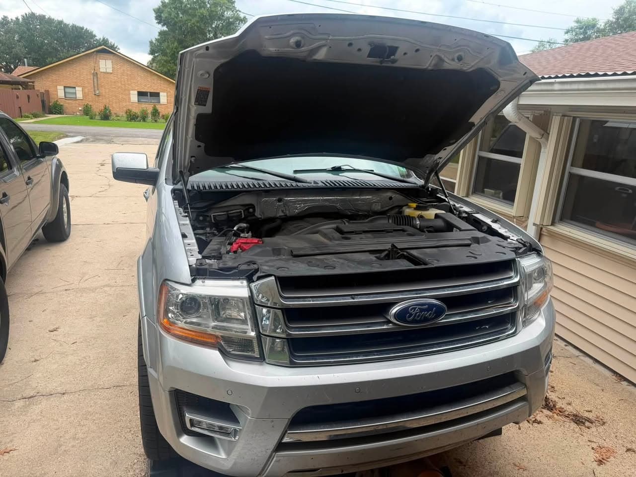 A Ford Expedition with the hood up in a residential driveway during a Bayou Boyz mobile maintenance visit